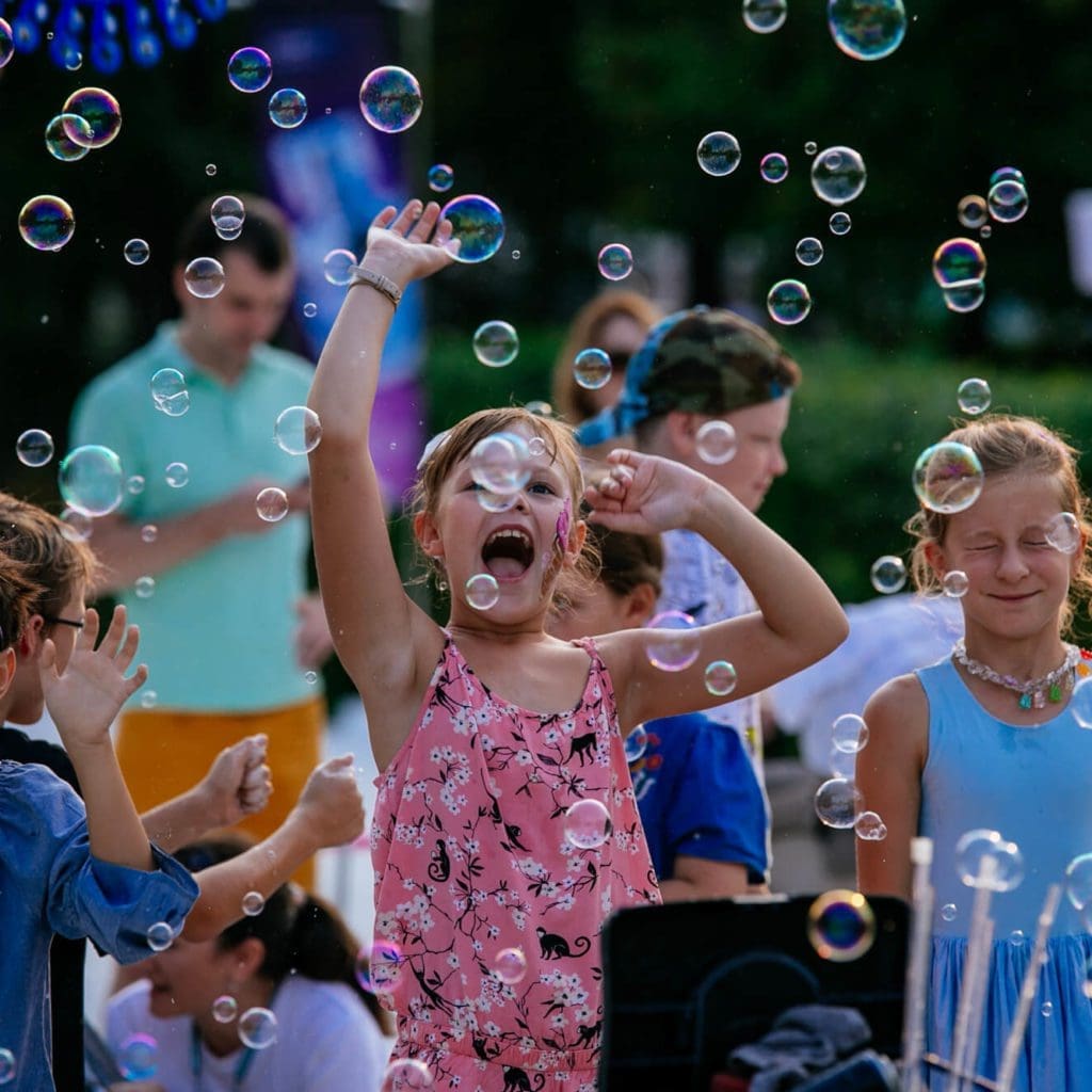 Дети смеются, играя с пузырями